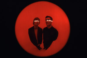 Fotografia de Bob Moses con un fondo rojo